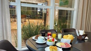A breakfast table with plates of food, a coffee cup, and a juice glass. - Hotel Transamerica Maringá (Maringá)