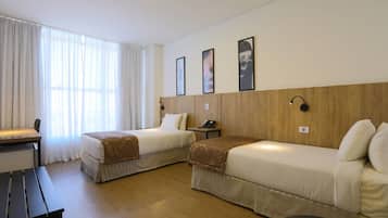 Una habitación de hotel con dos camas individuales, un escritorio y una silla.