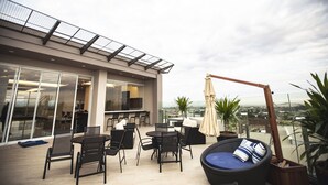 An outdoor terrace with a dining area, seating, and a view of the city. - Hotel Transamerica Maringá (Maringá)