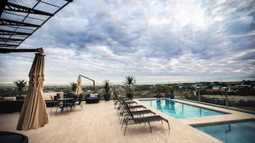 Una piscina al aire libre, sillones reclinables de piscina