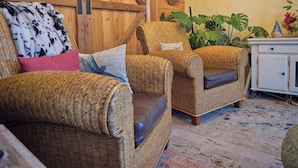 A cozy room with wicker furniture, a guitar wall decor, and a rustic wooden wall. - The Crest Motel in Colorful Colorado (Sterling)