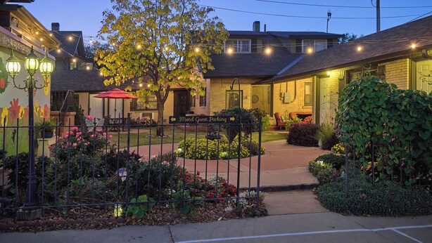 A motel with a garden area, outdoor seating, and a sign indicating guest parking. - The Crest Motel in Colorful Colorado (Sterling)