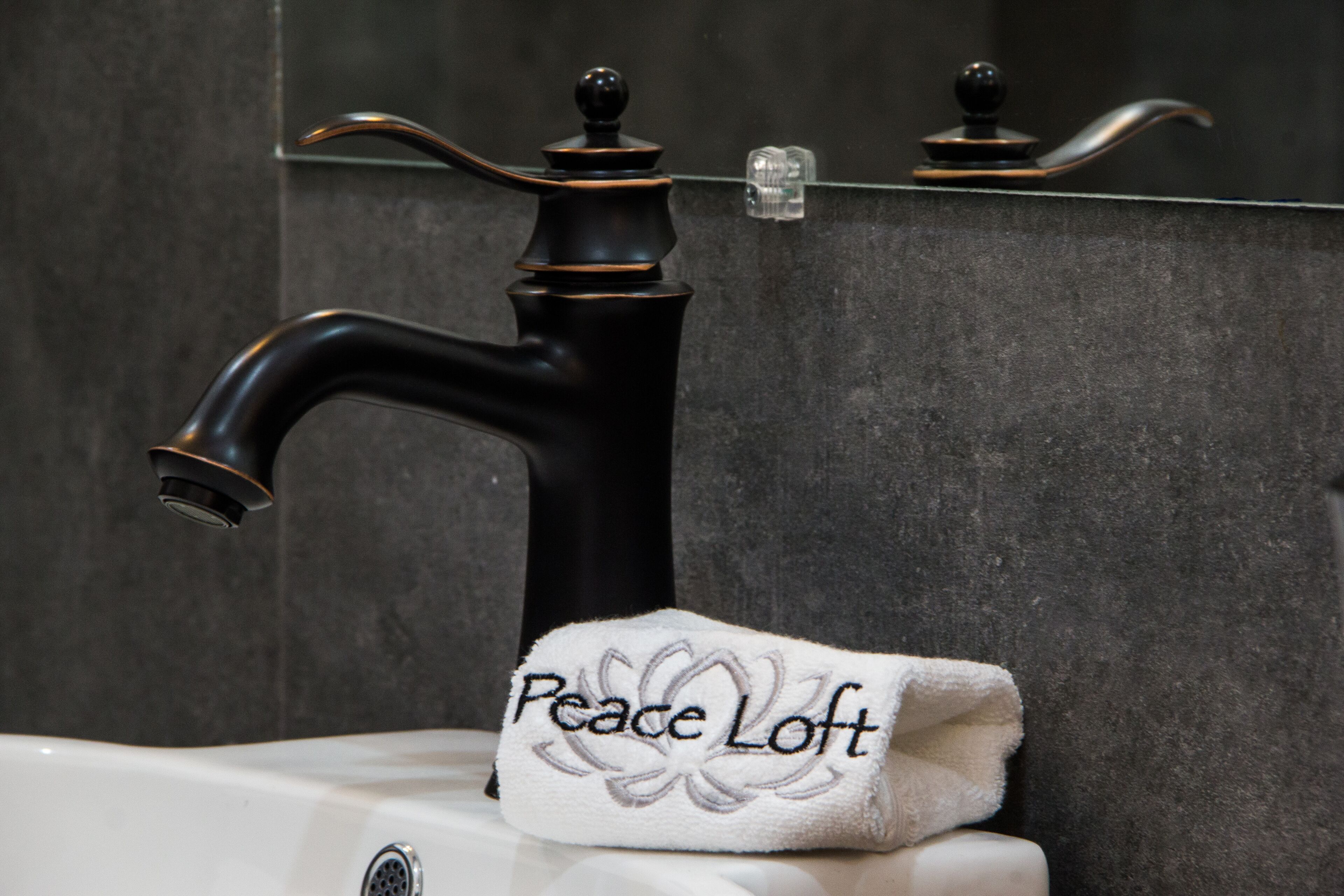 Ein Waschbecken mit Handtuch mit dem Aufdruck "Peace Loft" und einem Spiegel darüber.