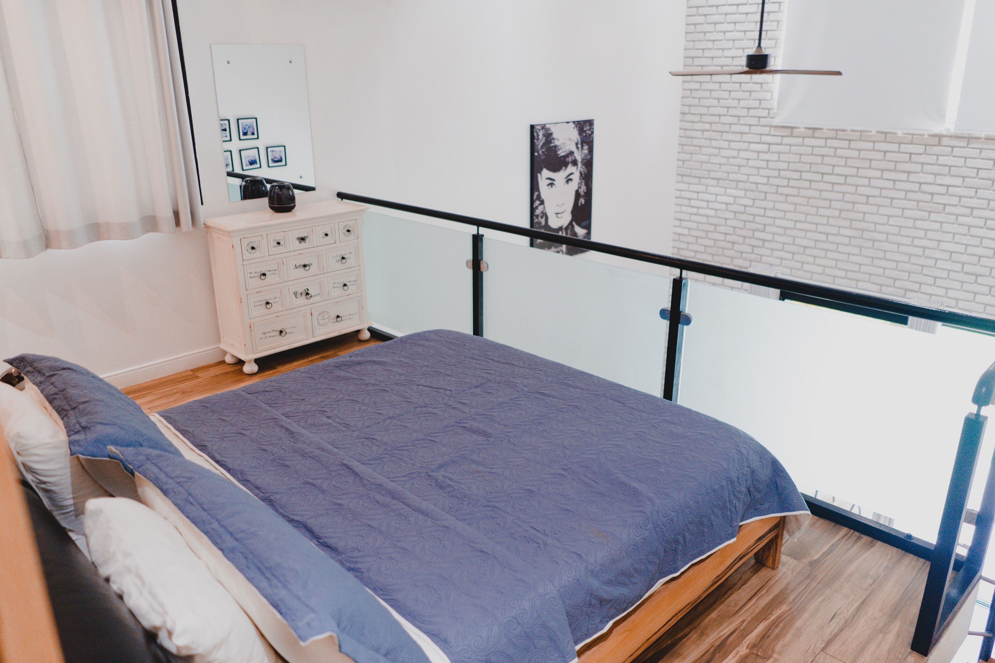 Een slaapkamer met een bed, een dressoir en uitzicht.