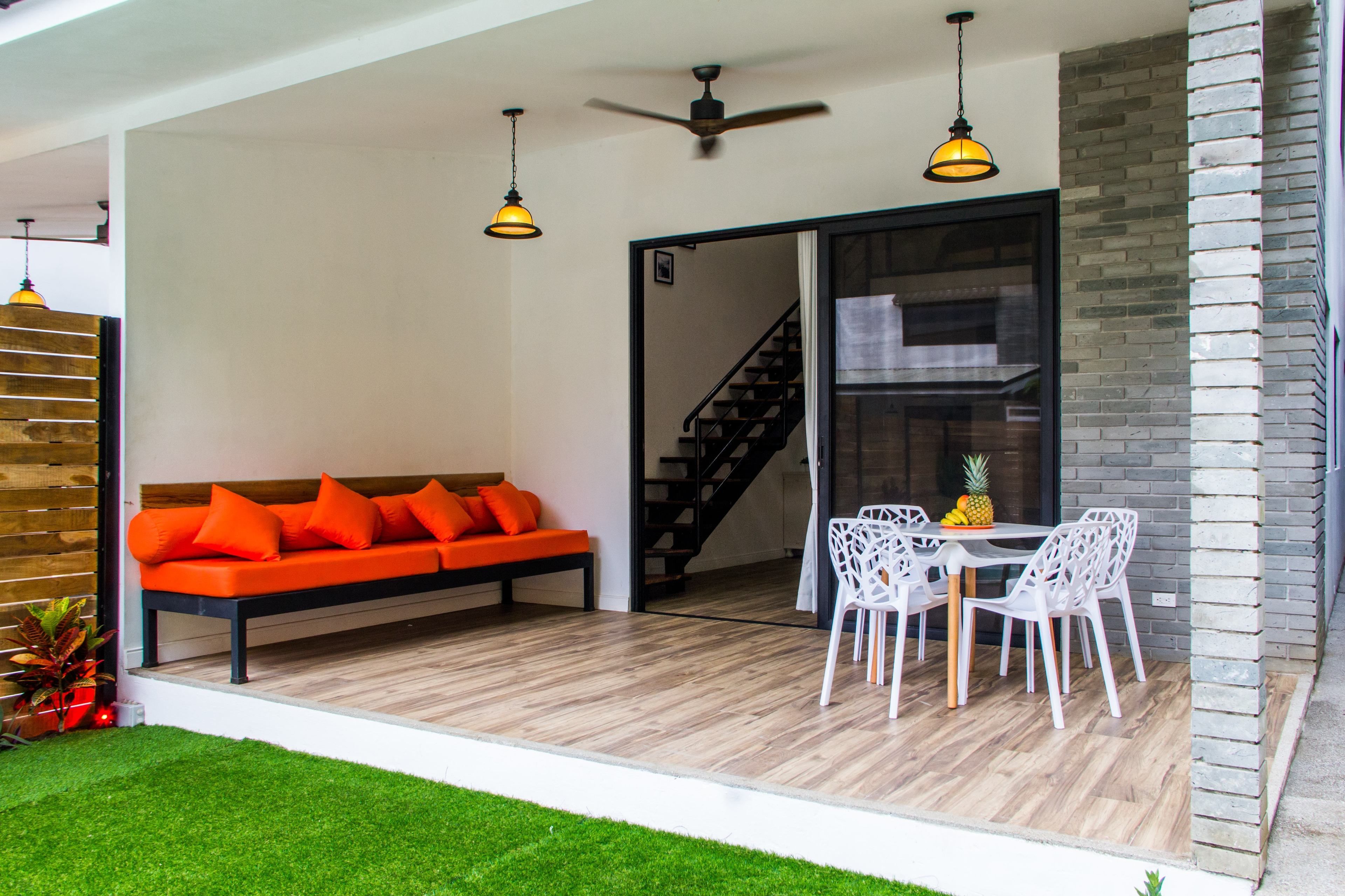A modern living area with a sofa, dining table, chairs, and a staircase.