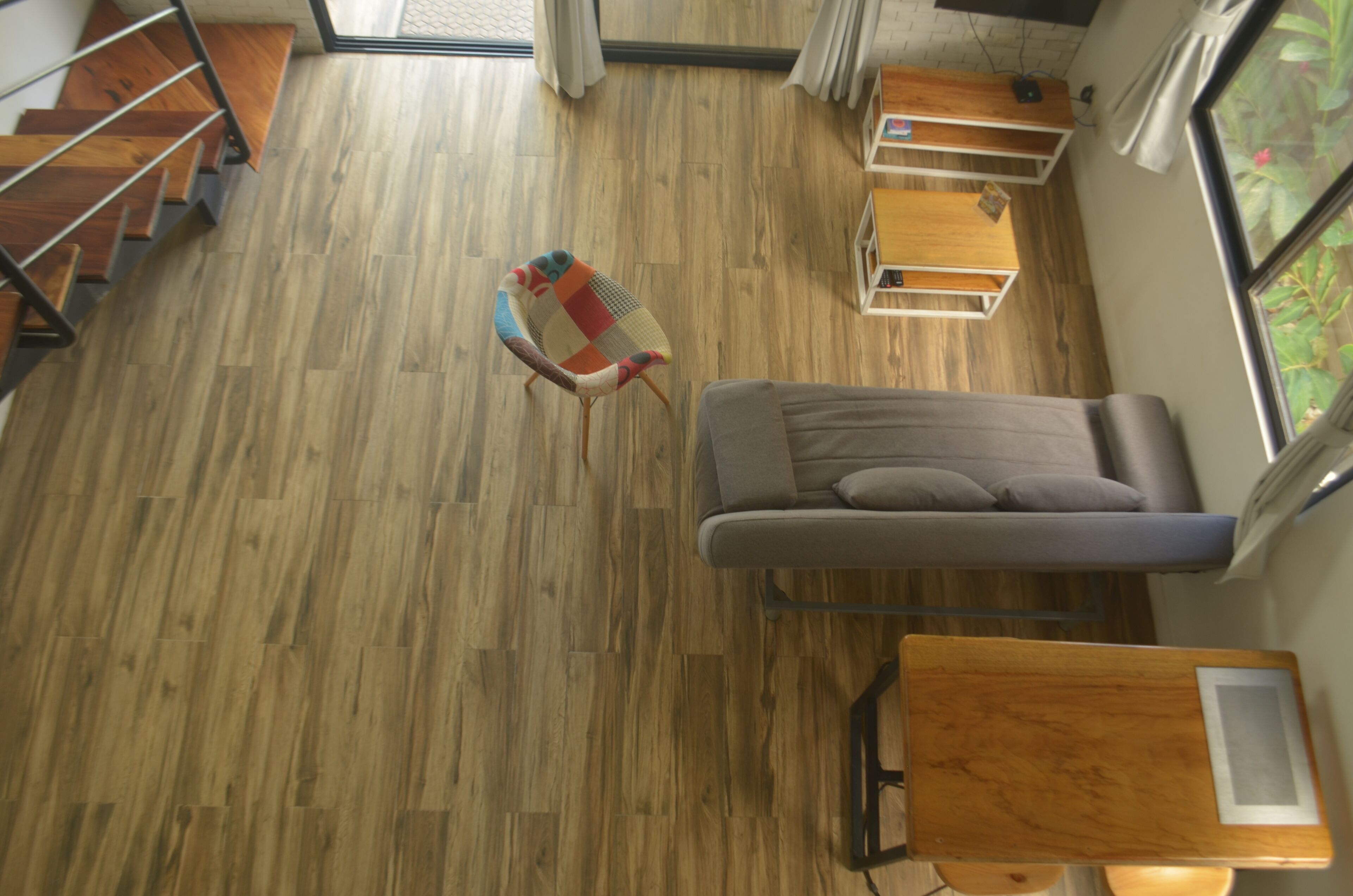 Un interior moderno con suelo de madera, un sofá, una mesita y una silla.