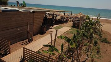 A beachside wooden structure with outdoor seating and a view of the sea.