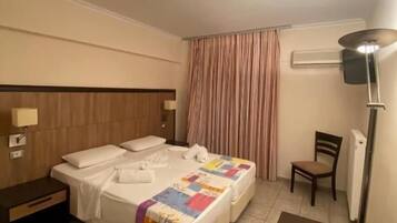 A hotel room with a double bed, a nightstand, a chair, a desk, and a lamp.