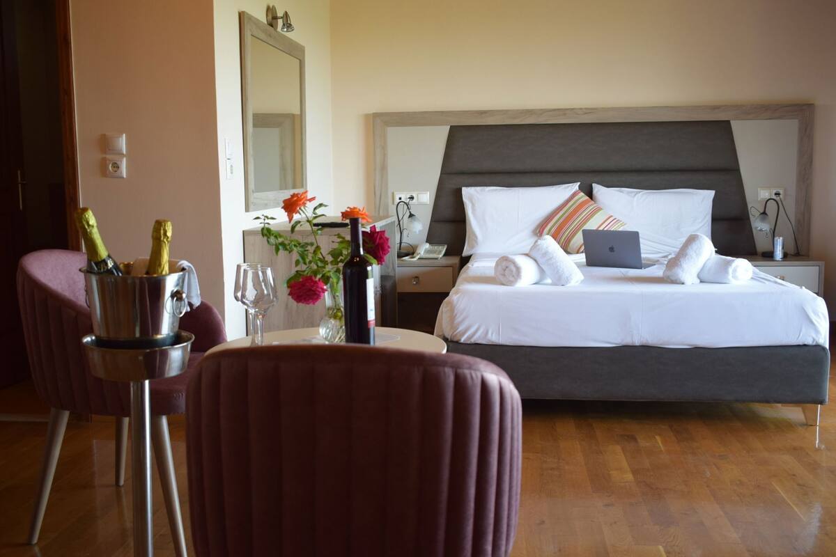 A hotel room with a bed, bedside table, lamp, and a chair.