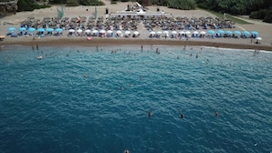 Una playa con muchos sombrillas y gente nadando en el agua.