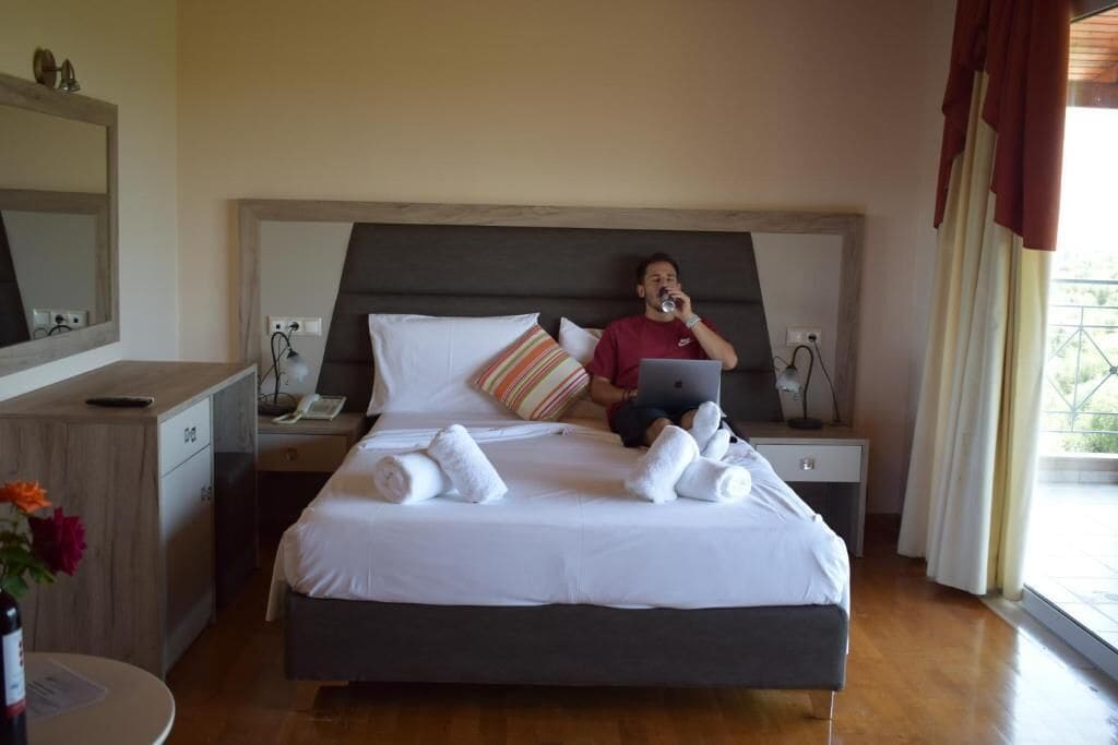 Habitación de hotel con cama, escritorio, silla, espejo y ventana.
