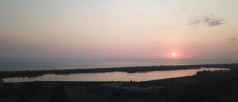 A sunset over a body of water with land in the foreground.
