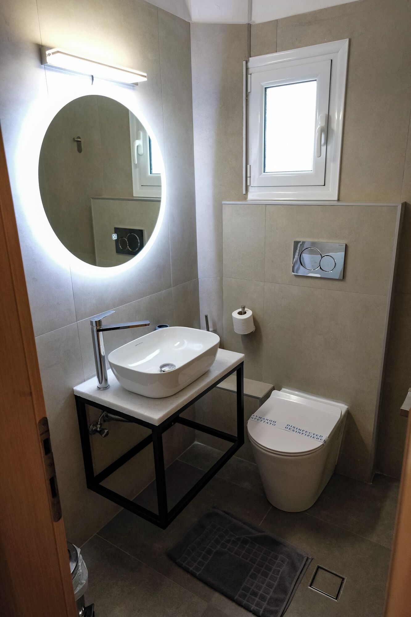 Un baño pequeño con un espejo redondo, un lavabo blanco y un inodoro.