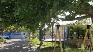 Un columpio bajo un árbol, un muro de piedra y un mural en un edificio al fondo.