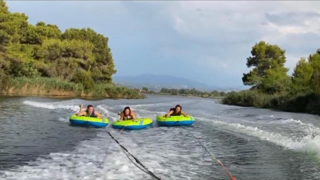 Three people on a raft in a river surrounded by greenery.