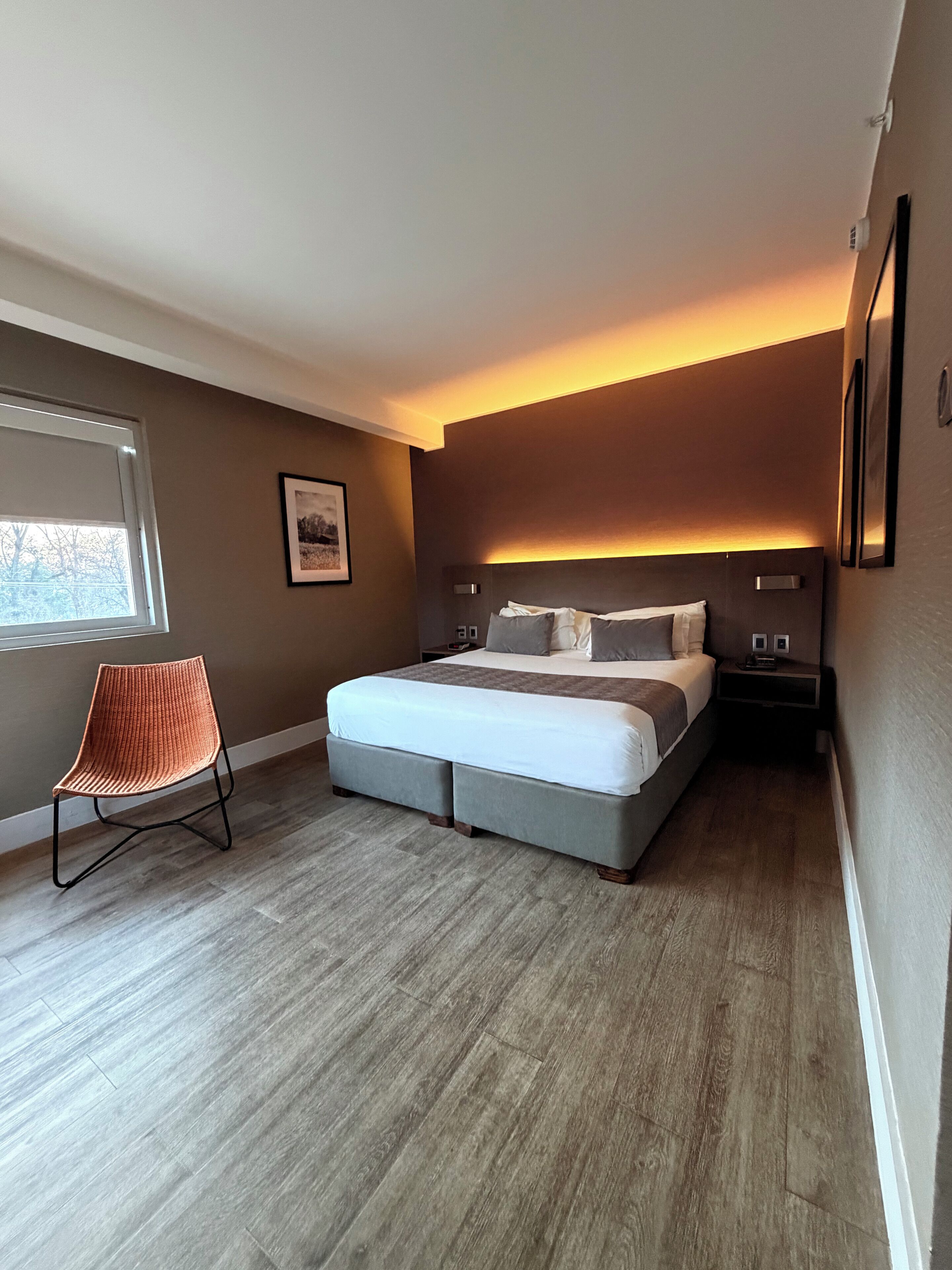 A modern bedroom with a large bed, a chair, and a nightstand.