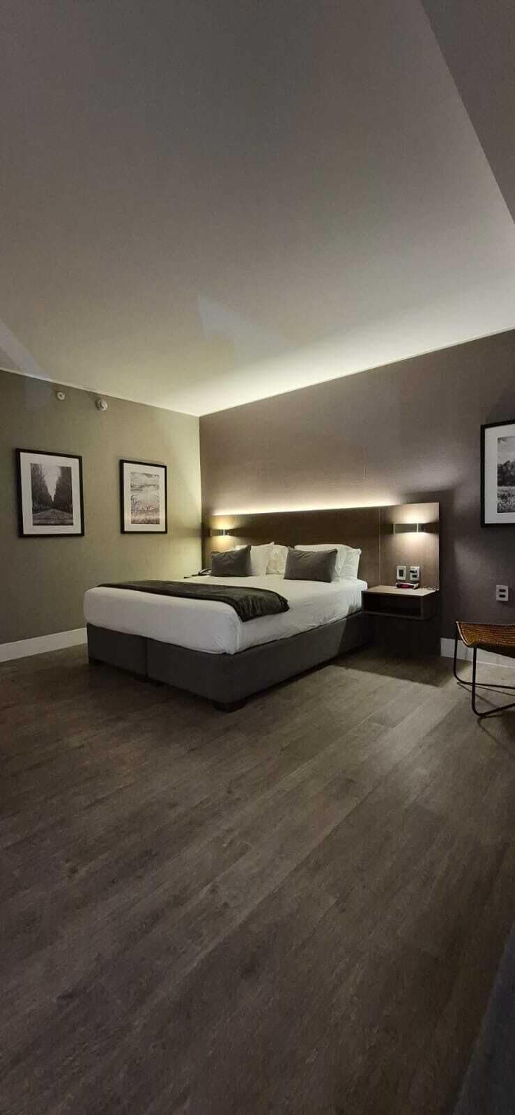 Quarto moderno com cama, mesas de cabeceira e iluminação embutida na parede.