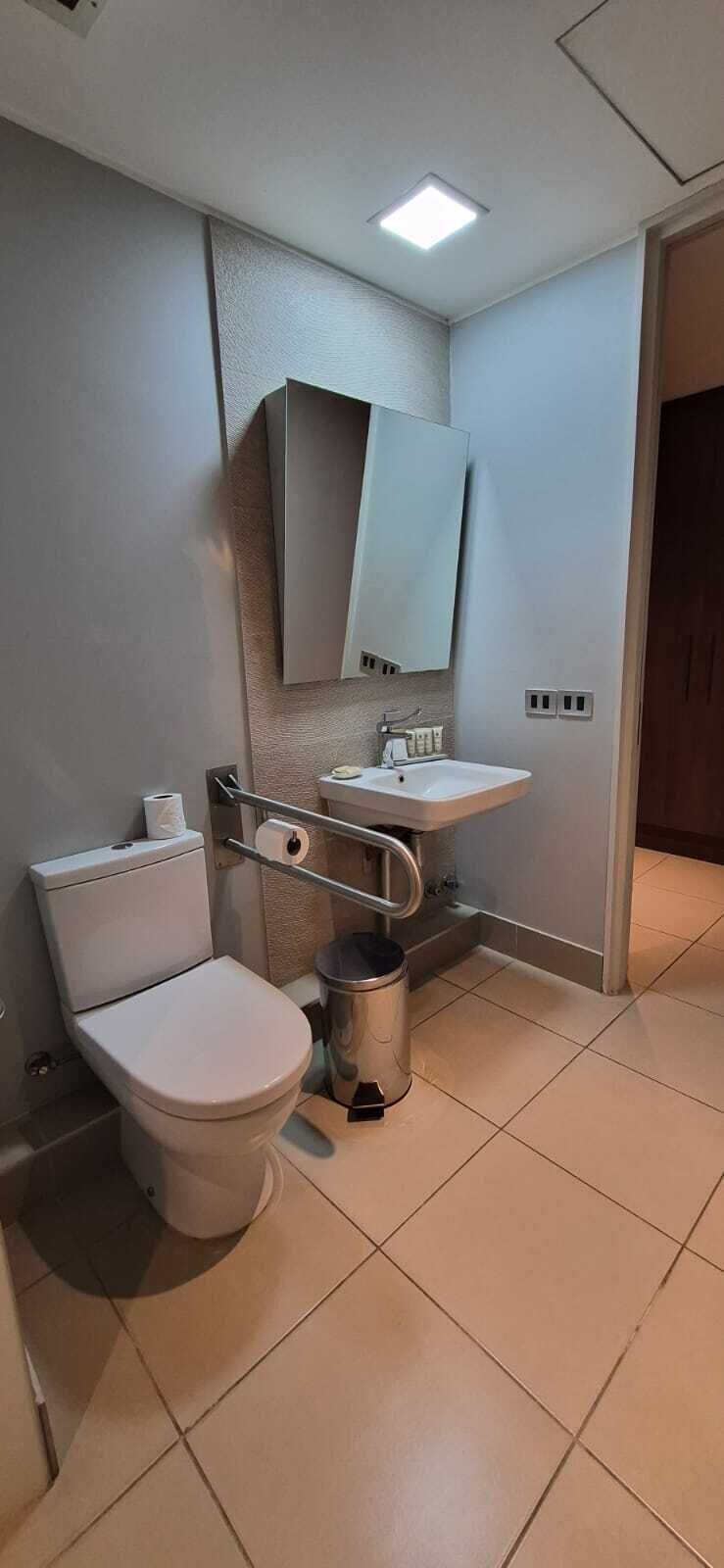 A small bathroom with a toilet, sink, and mirror.