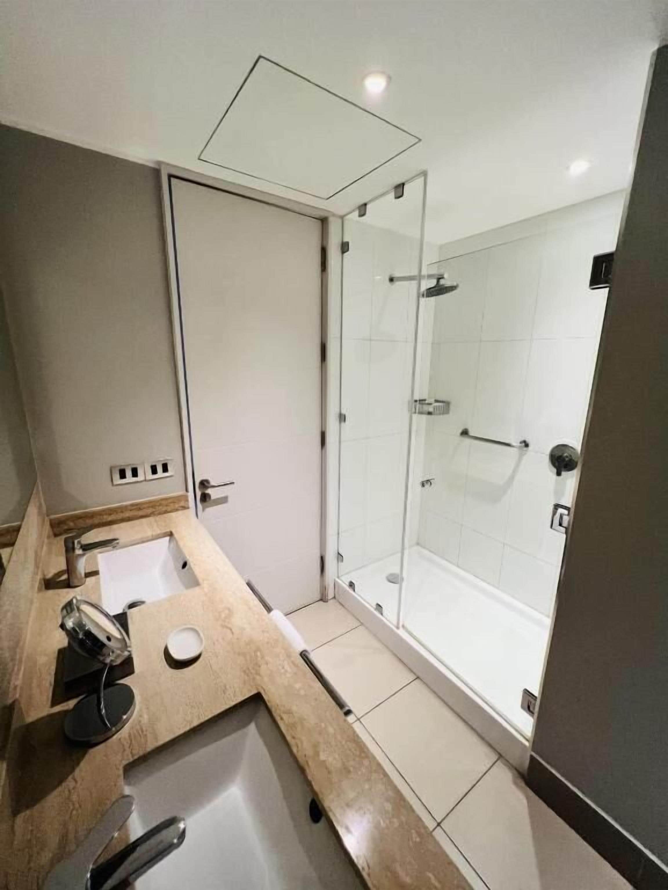 Een moderne badkamer met een douchecabine van glas, een wastafel met spiegel en een toilet.