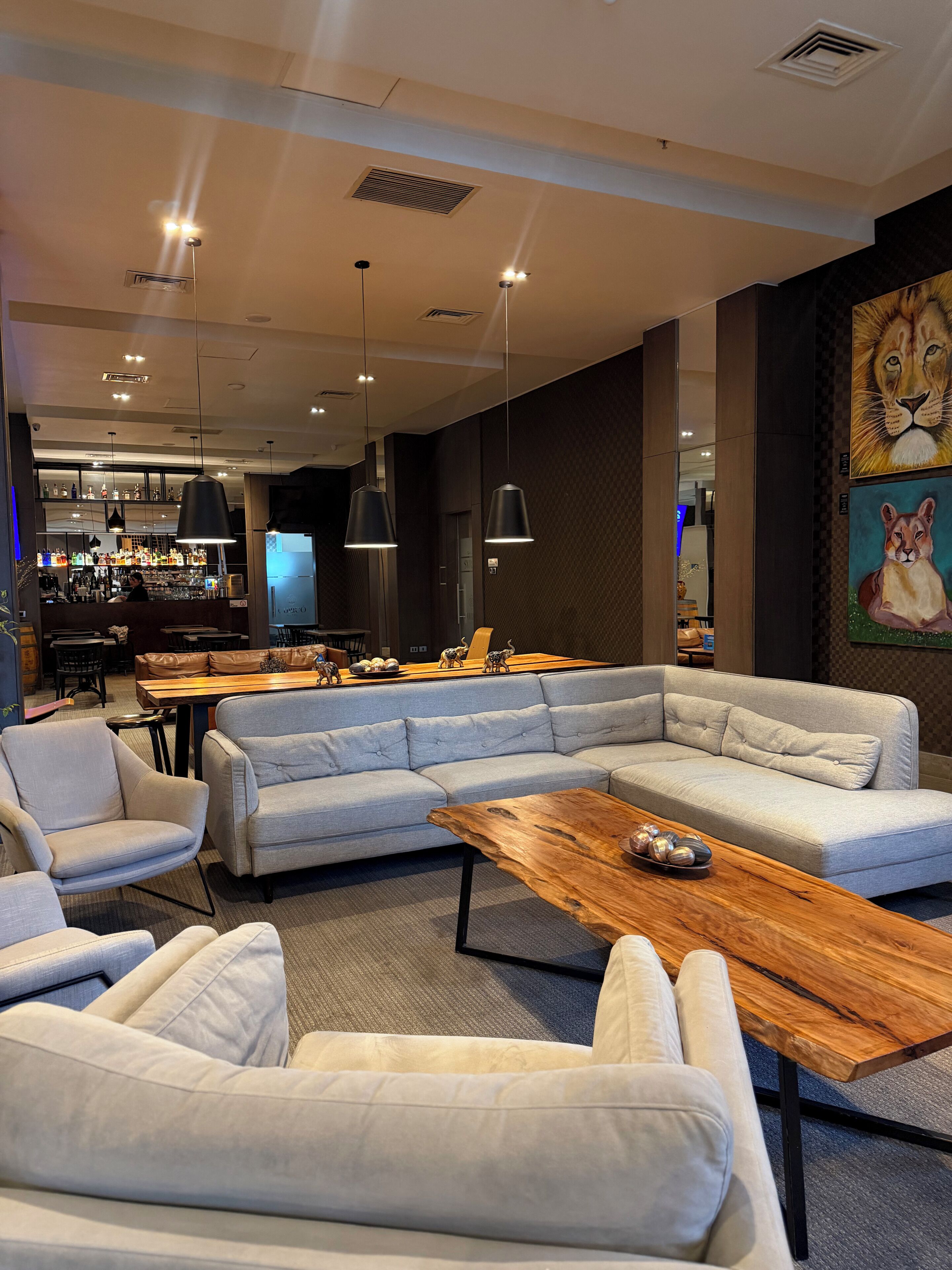 A modern lounge area with a sectional sofa, a wooden coffee table, and pendant lighting.