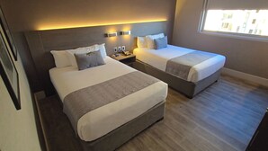 A hotel room with two beds, bedside tables, a phone, and a window. - Hotel Curicó (Curicó)