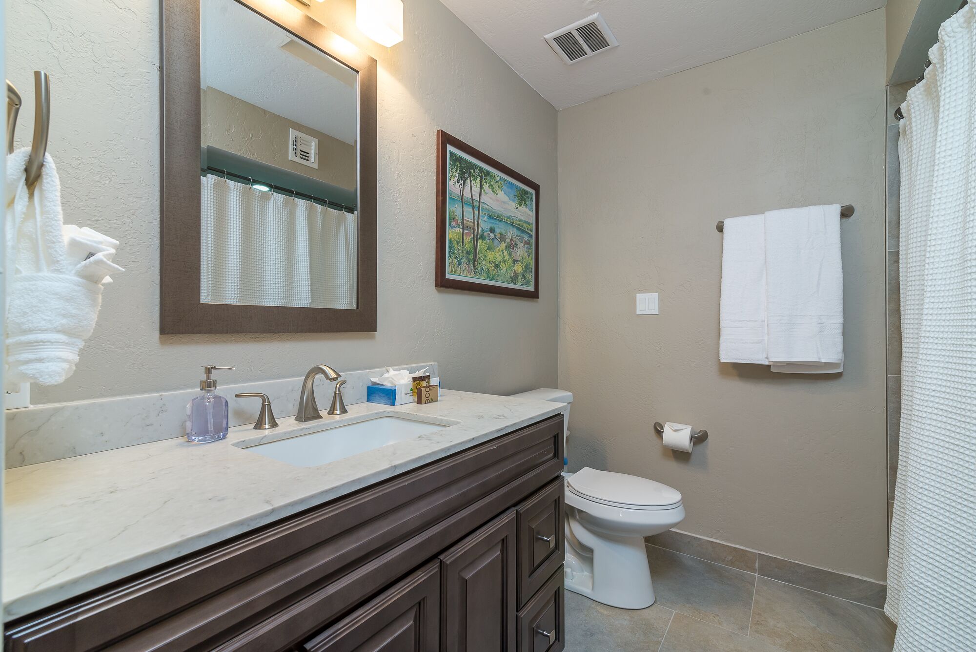 A bathroom with a marble sink, a toilet, and a shower curtain.