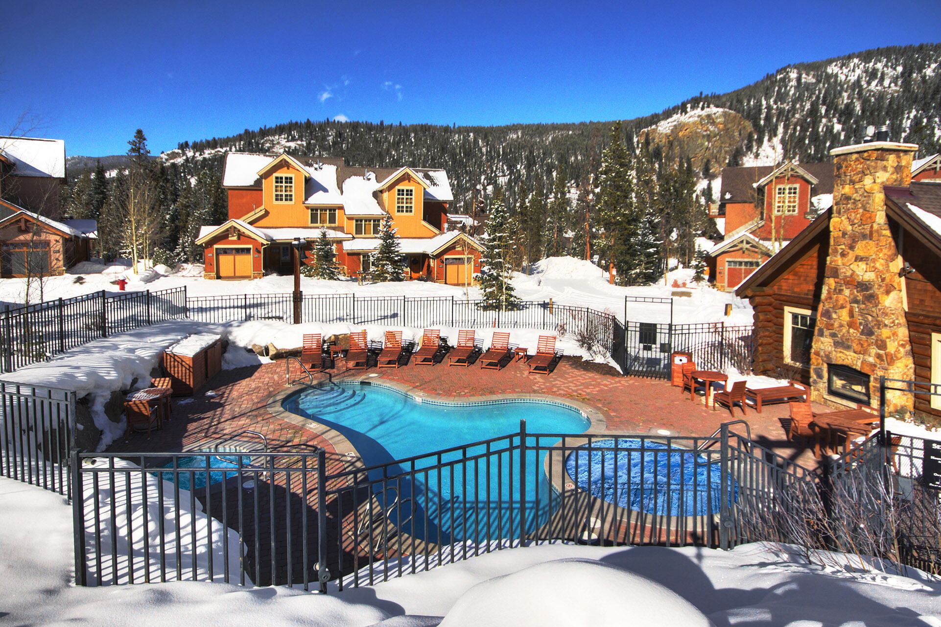 A pool area with lounge chairs and a stone building.