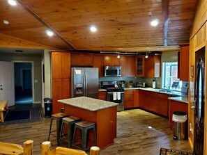 Enjoy cooking in this well-equipped kitchen with a central island, stainless steel appliances, and a sink with a window above.