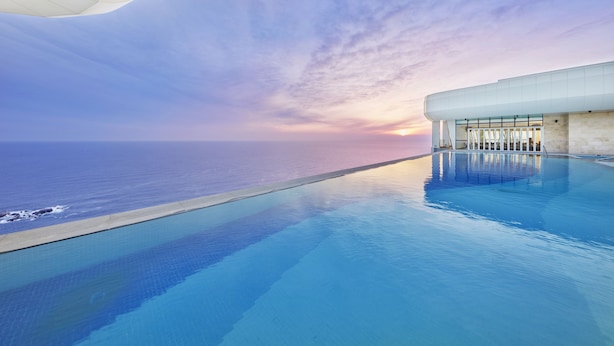 A modern infinity pool with a clear view of the ocean at sunset. - Skybay Hotel Gyeongpo (Gangneung)