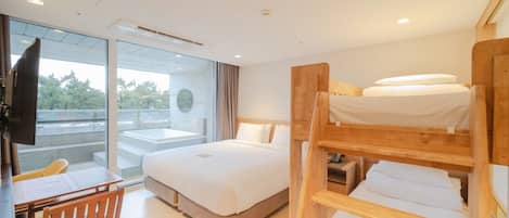 Habitación de hotel moderna con una cama grande, un escritorio con una silla y un balcón con vistas a árboles.