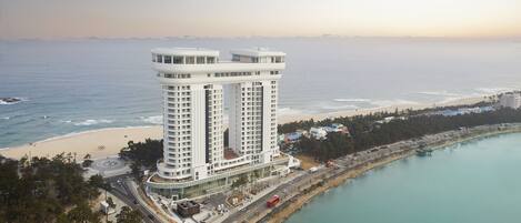 A high-rise hotel with a modern design, located near a beach and a body of water.