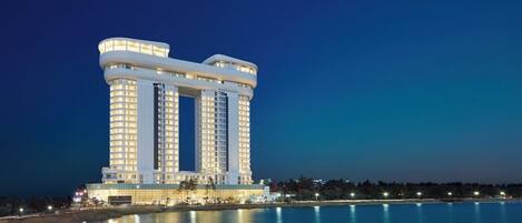 A high-rise hotel with multiple floors and balconies, situated by a body of water.
