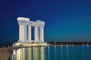 Un grand hôtel à plusieurs étages, doté de nombreux balcons, situé au bord d’un plan d’eau.