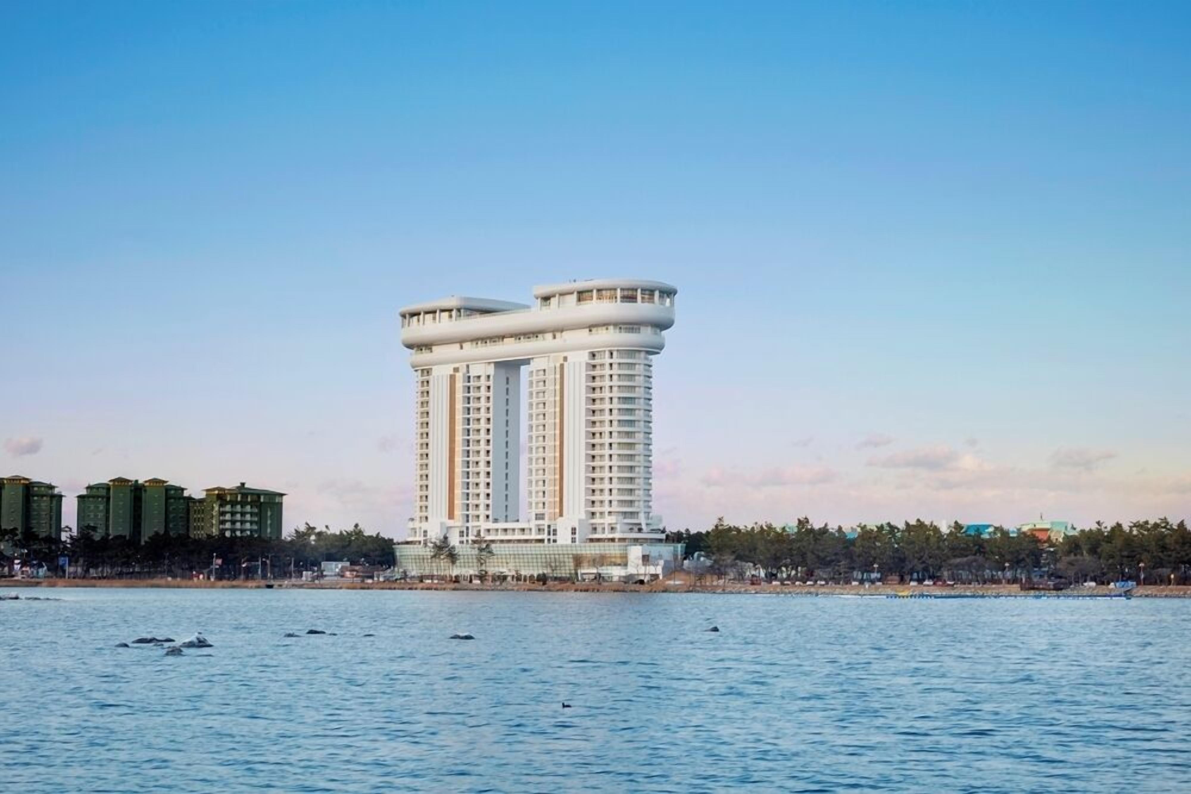 Un hotel moderno y alto de diseño cilíndrico peculiar, situado cerca de la costa con vistas claras al mar.