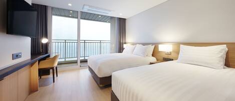 Habitación de hotel con dos camas, un escritorio, un televisor y un balcón con vistas.
