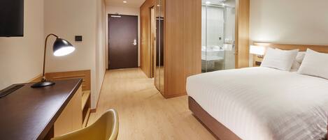 Een hotelkamer met een bed, bureau, stoel en een spiegel.