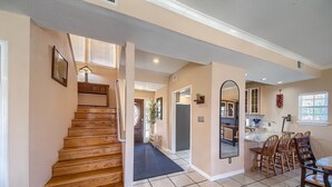 A spacious interior with a wooden staircase, a kitchen area with a dining table and chairs, and a hallway leading to a bathroom. - Players Place PRD2462 (New Braunfels)