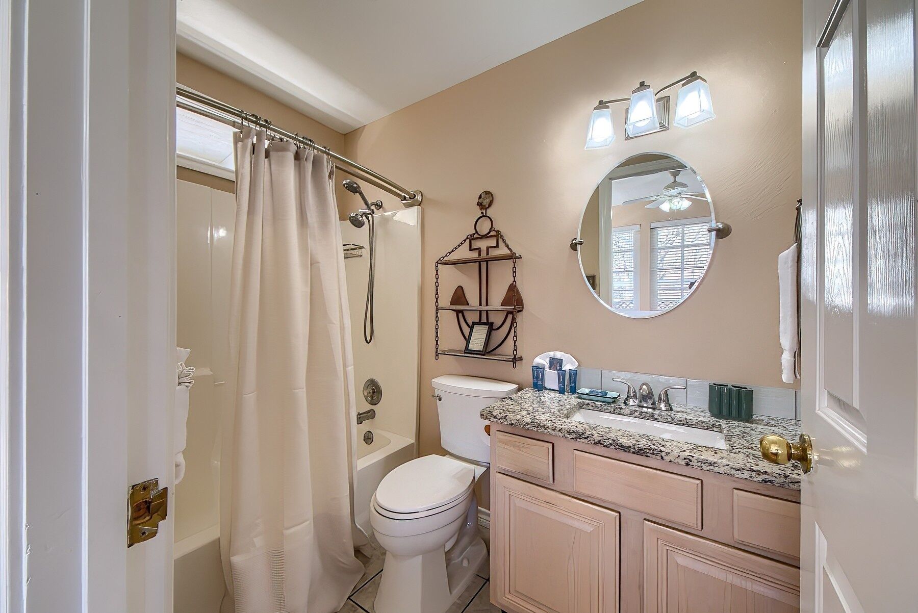 A bathroom with a shower curtain, toilet, sink, and vanity.