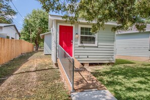 A small, single-story house with a red door and a small porch.