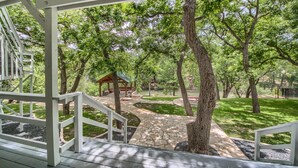 A covered outdoor area with a stone pathway, wooden deck, and a gazebo. - Players Place PRD2462 (New Braunfels)