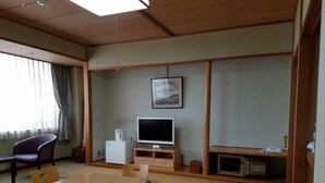 A traditional Japanese-style room with tatami flooring, a wooden table, and a television.