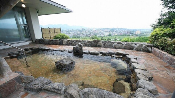 A hot spring area with a stone border and a view of a city in the background.
