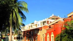 A colonial-style building with a red facade, arched windows, and a central courtyard. - Condominio SDM Chahue 2BR (Santa María Huatulco)