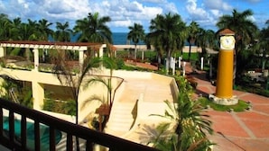 A resort with a pool, palm trees, and a clock tower. - Condominio SDM Chahue 2BR (Santa María Huatulco)