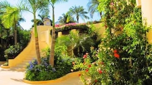 A tropical resort with palm trees, a curved pathway, and lush greenery. - Condominio SDM Chahue 2BR (Santa María Huatulco)