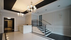 Eine großzügige Lobby mit einer imposanten Treppe, einer Rezeption und eleganten Kronleuchtern.