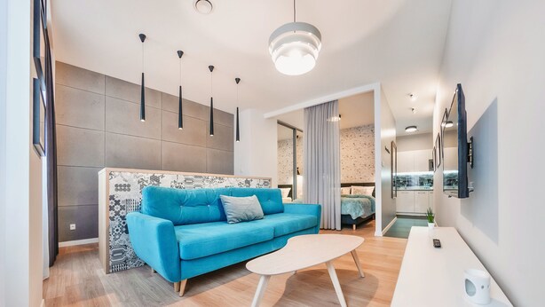 Ein modernes Wohnzimmer mit einem blauen Sofa, einem weißen Couchtisch und Pendelleuchten.