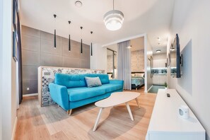A modern living room with a blue sofa, a white coffee table, and pendant lighting. - Tartaczna Old Town (Gdansk)