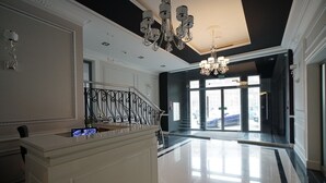 Eine geräumige Lobby mit einer imposanten Treppe, einem Empfangsbereich und einem Kronleuchter.