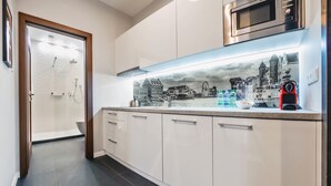 Eine moderne Küche mit weißen Schränken, einer Edelstahl-Mikrowelle und einer städtischen Spritzschutzwand.